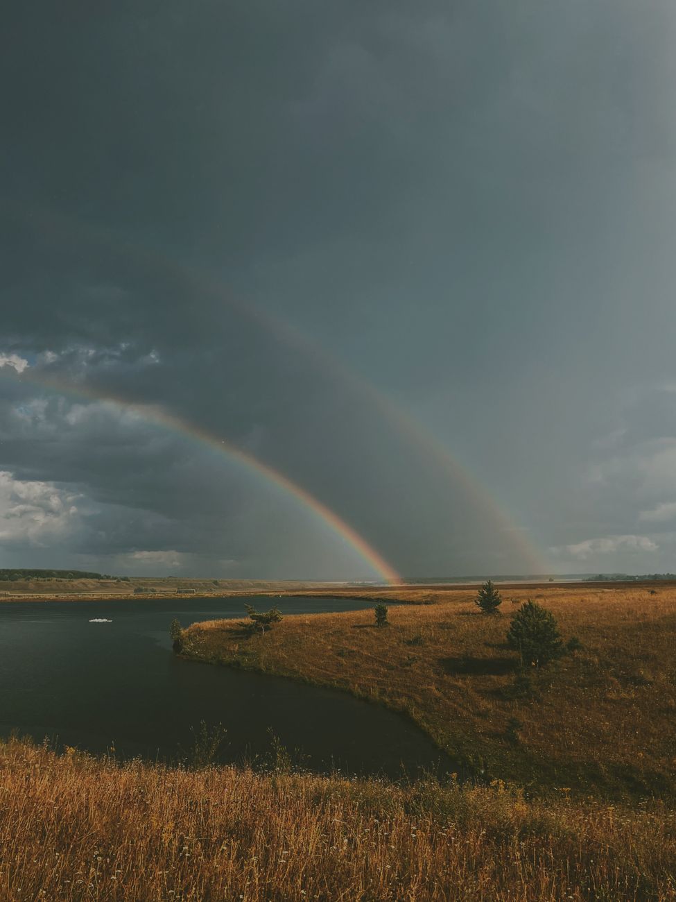 double rainbow above river running through field